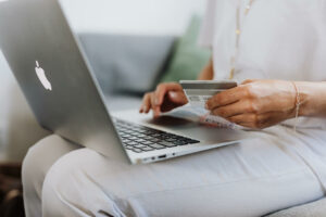 Woman wearing all white sitting with laptop and holding a credit card